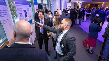 Guests at a fancy event reading signage about the quantum computer